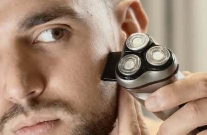 muž používa holiaci strojček na tvár